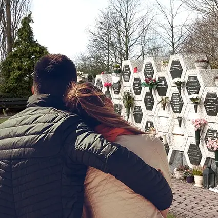 Nabestaanden bij een urnenmuur op een begraafplaats