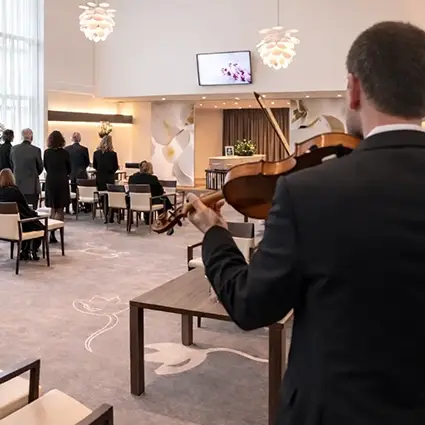 Afscheidsdienst met aanwezigen en live vioolmuziek in een uitvaartcentrum