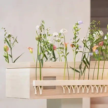 Lichte houten uitvaartkist met natuurlijke bloemen uit de kistencollectie van Hess uitvaartzorg