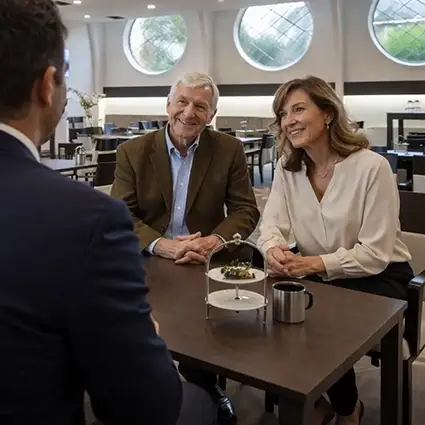 Adviseur in gesprek met echtpaar over uitvaartwensen in de rustige omgeving van rouwcentrum De Meidoorn