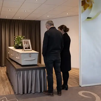 Nabestaanden nemen afscheid bij een gesloten kist in rouwcentrum Overschie