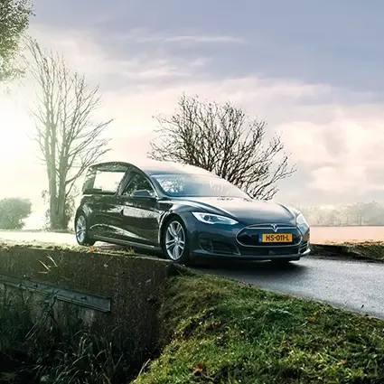 Elektrische Tesla rouwauto rijdt over landelijke weg bij zonsopkomst