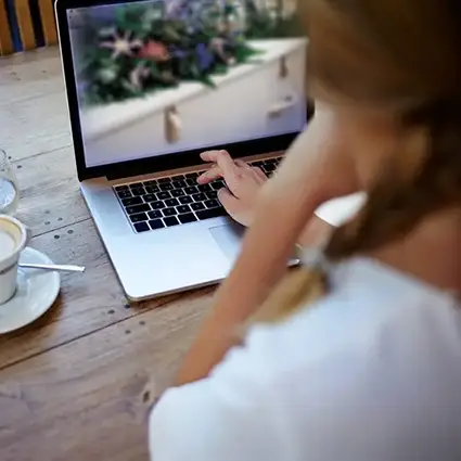 Persoon bekijkt uitvaartbeelden op laptop voor opslag op Hess memoriecard