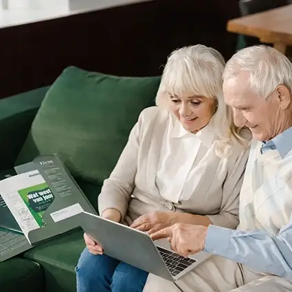 Echtpaar bekijkt thuis informatie en recensies over uitvaartzorg op een laptop